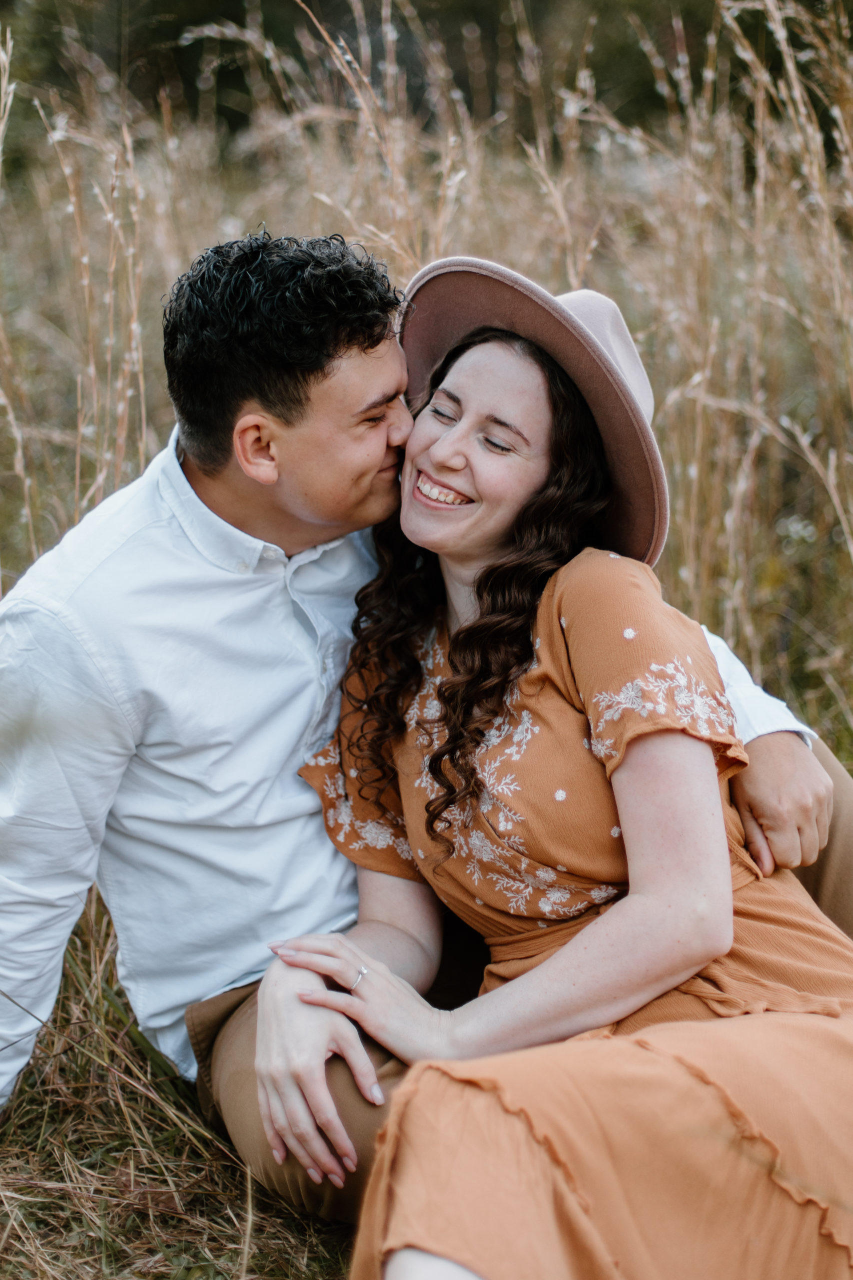 Beautiful couple sit together in a field during their golden hour Georgia engagement photos