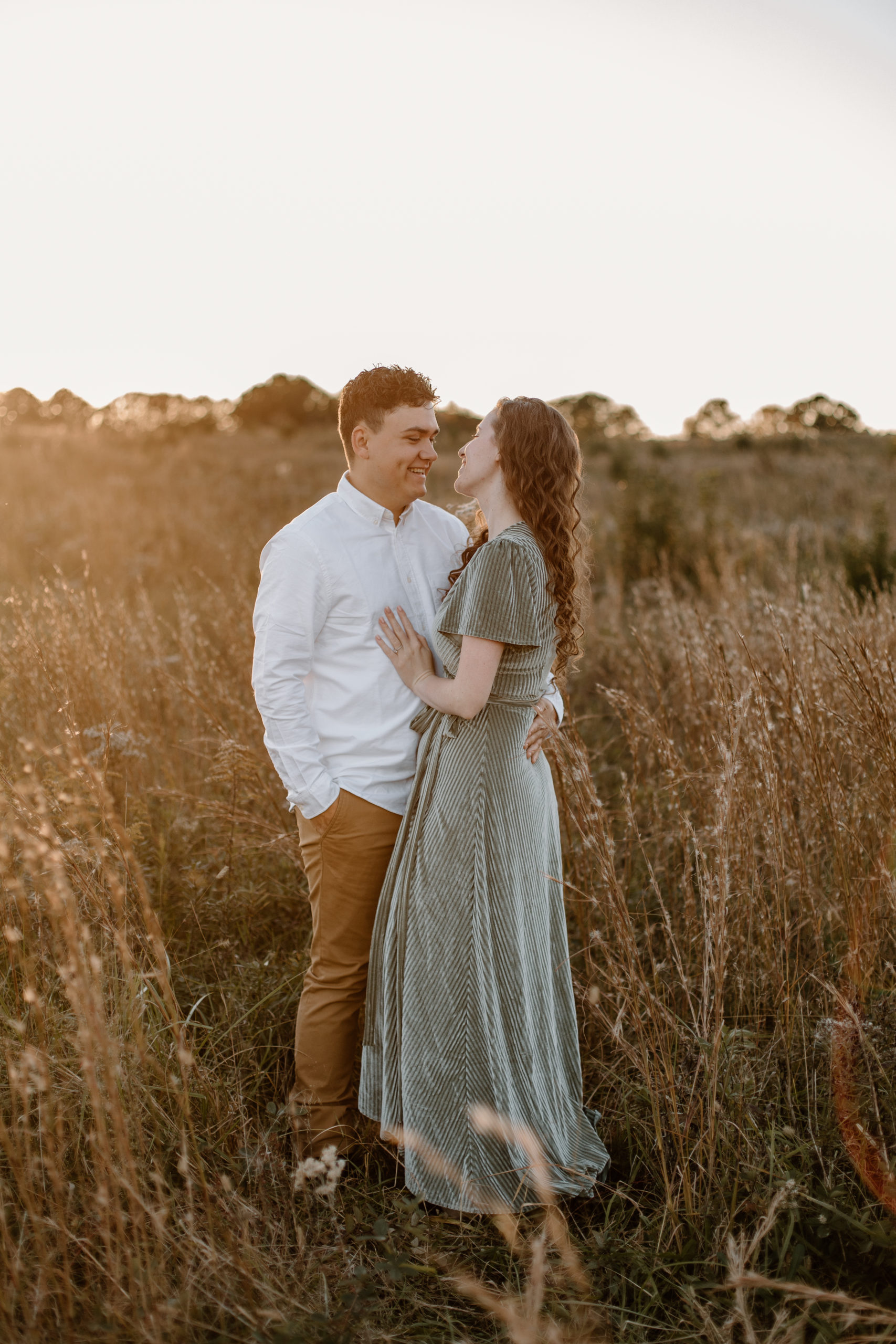 stunning couple pose in a Georgia field together during their golden hour engagement photos