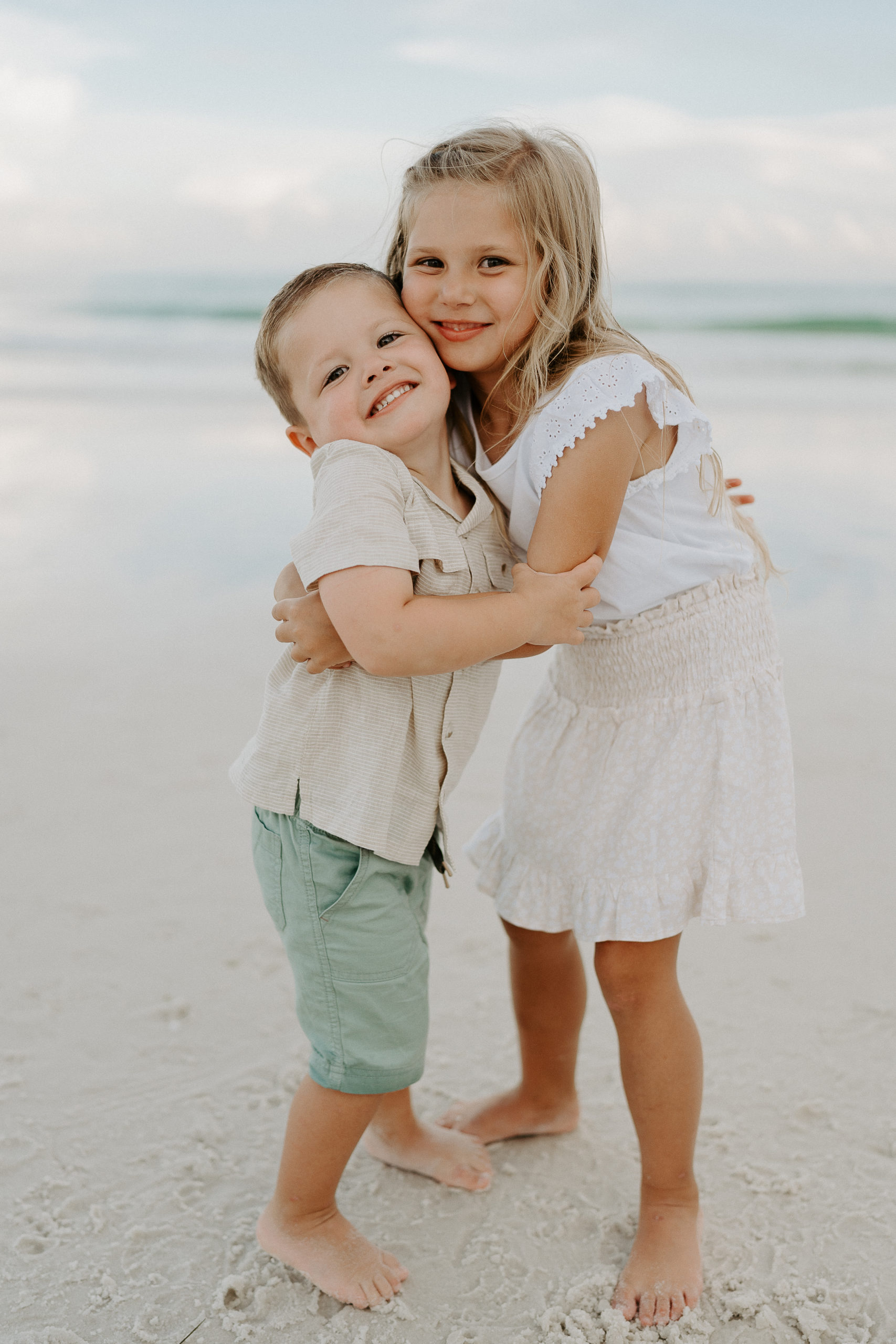 brother and sister hug each other on the beach