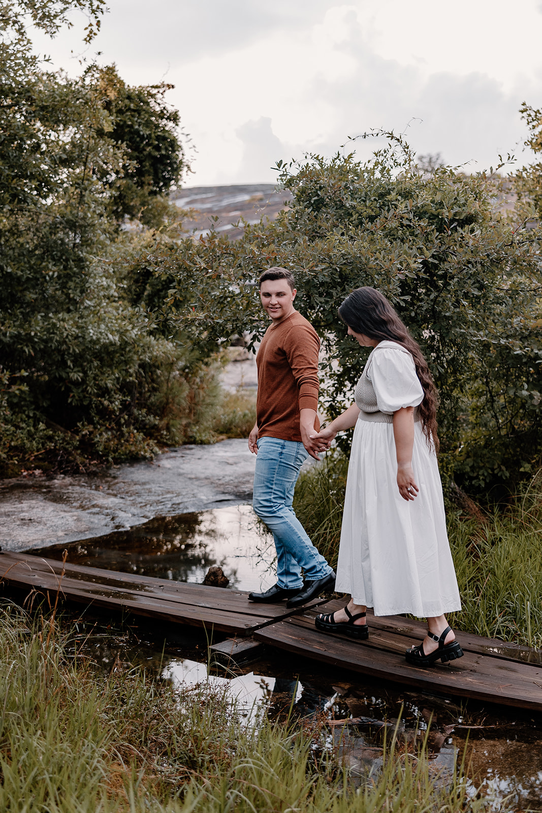 Adventure Couples Photo session walking up to mountainside with greenery and bridge. 