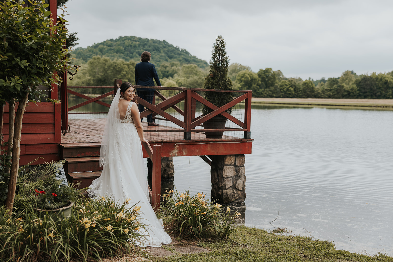 Bride at lake in front of red building. 