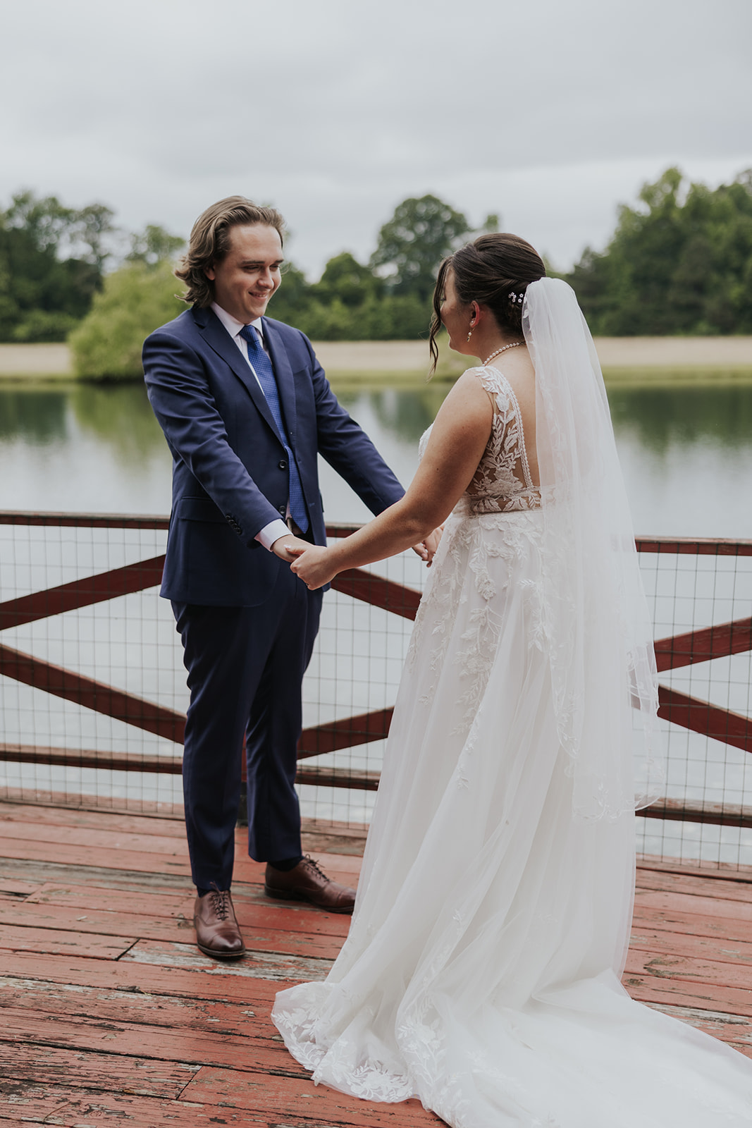 bride and groom dancing on dock by water.