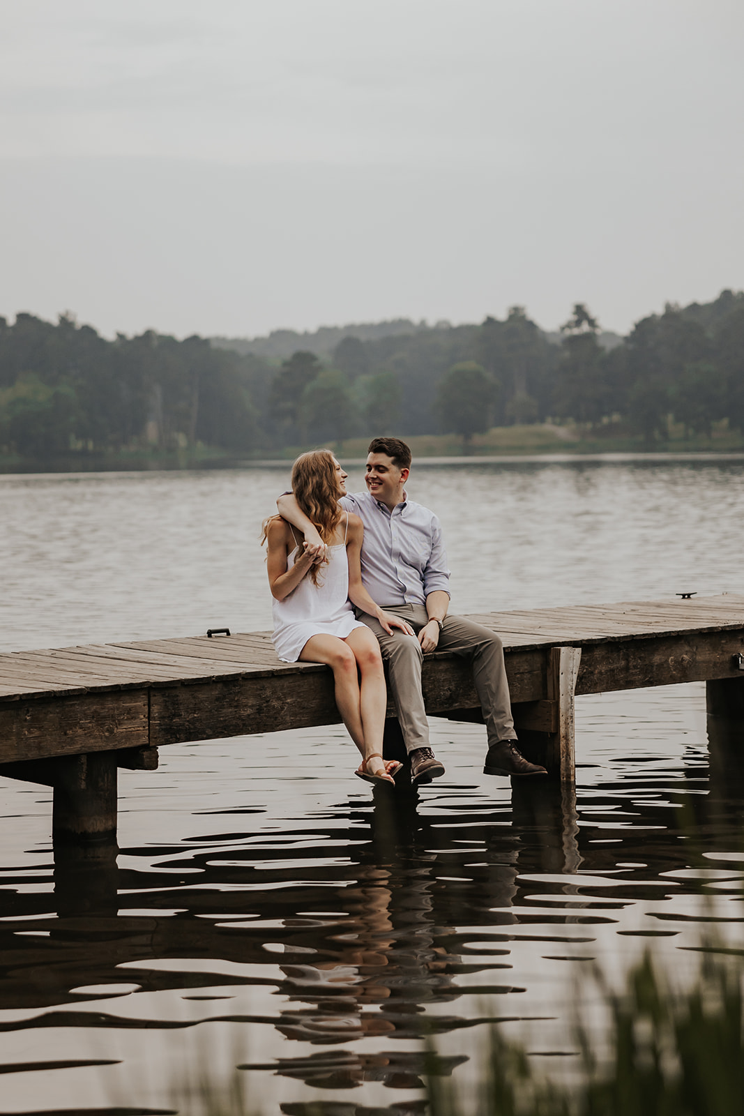 Beautiful couple sit together on a Lake Acworth dock during their engagement photoshoot. Such a cute couples photo idea