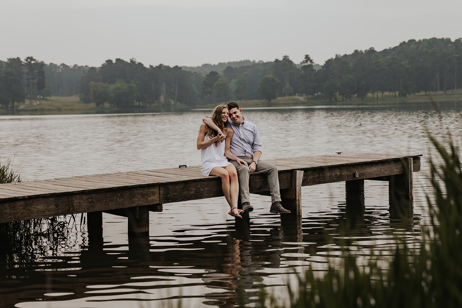 Beautiful couple sit together on a Lake Acworth dock during their engagement photoshoot.
