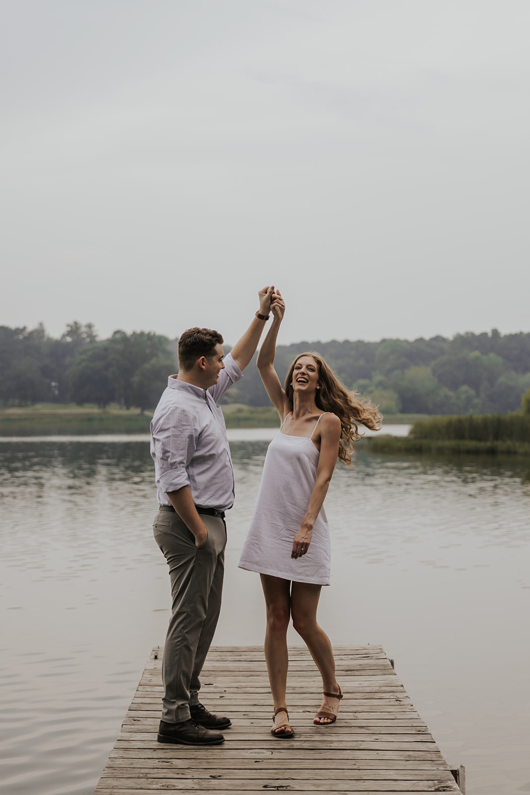 Beautiful couple dance together on a Lake Acworth dock during their engagement photoshoot. A simple and candid cute couple photo idea