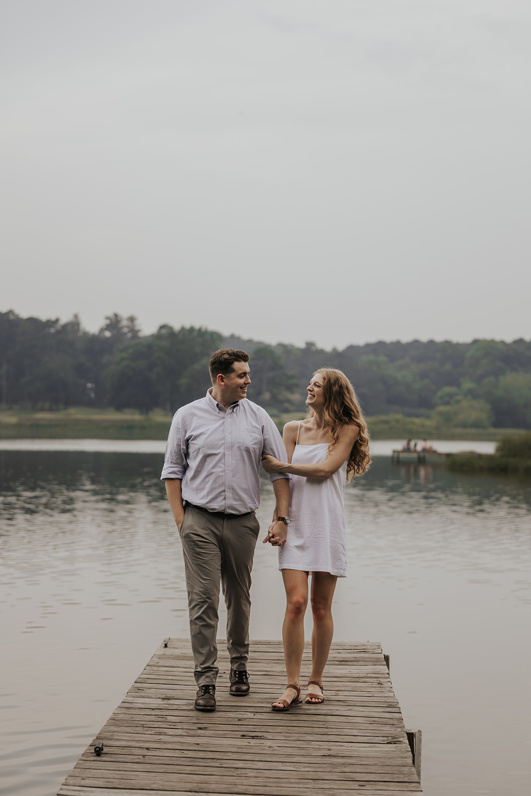 Stunning couple walk towards the camera during their engagement photoshoot on a dock in Georgia.