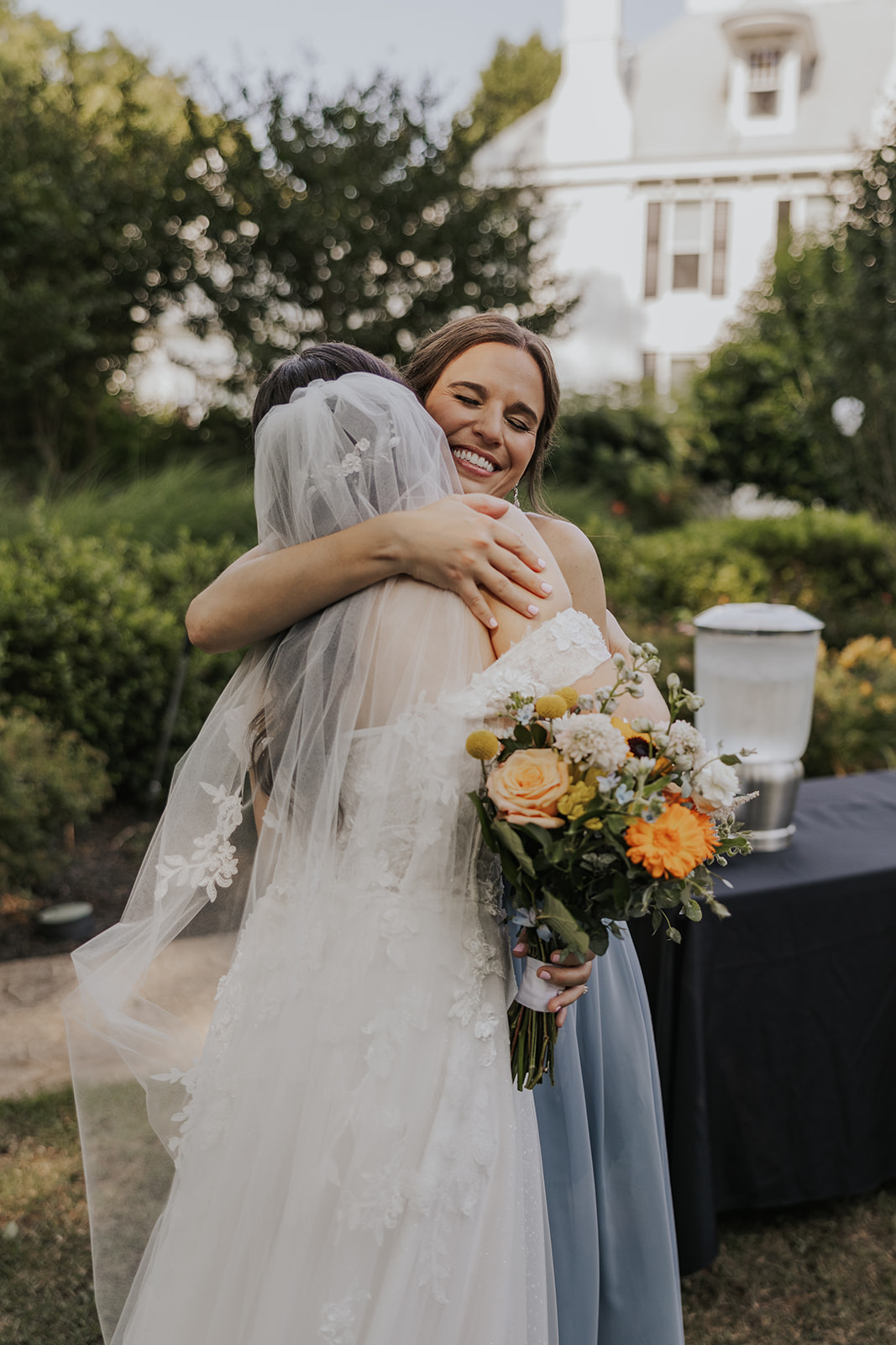 Beautiful bride shares a hug with a friend after her sentimental Georgia wedding