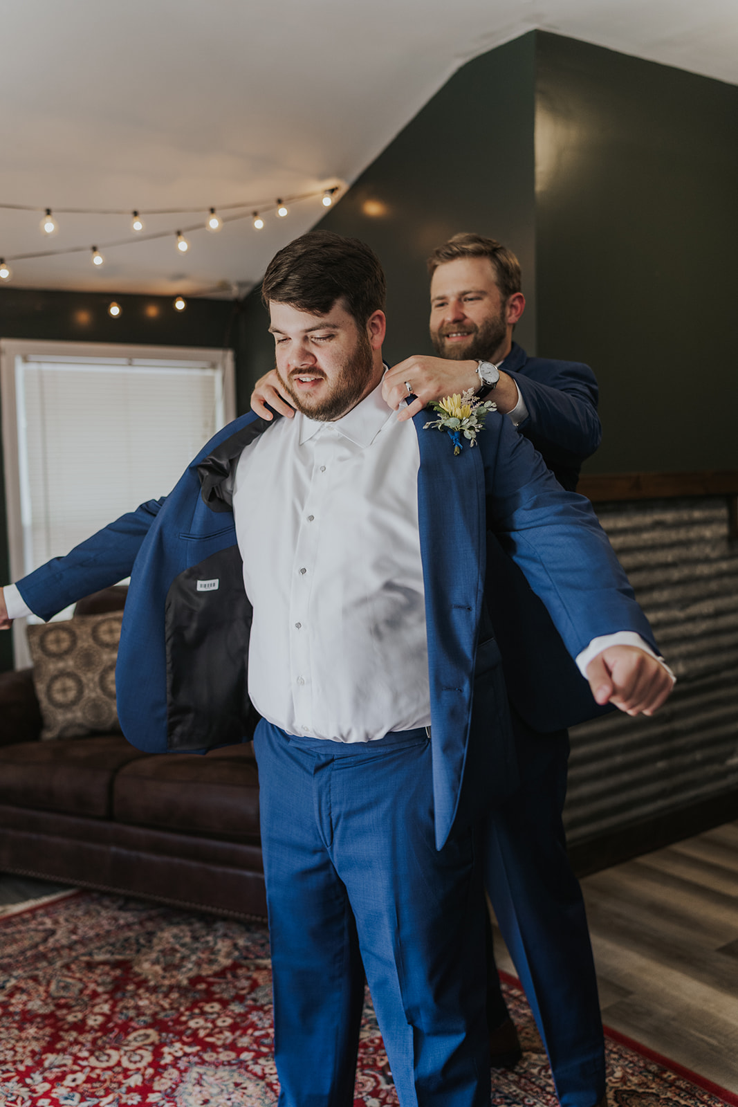 Best man helps the groom put his jacket on to finalize preparations for his wedding!