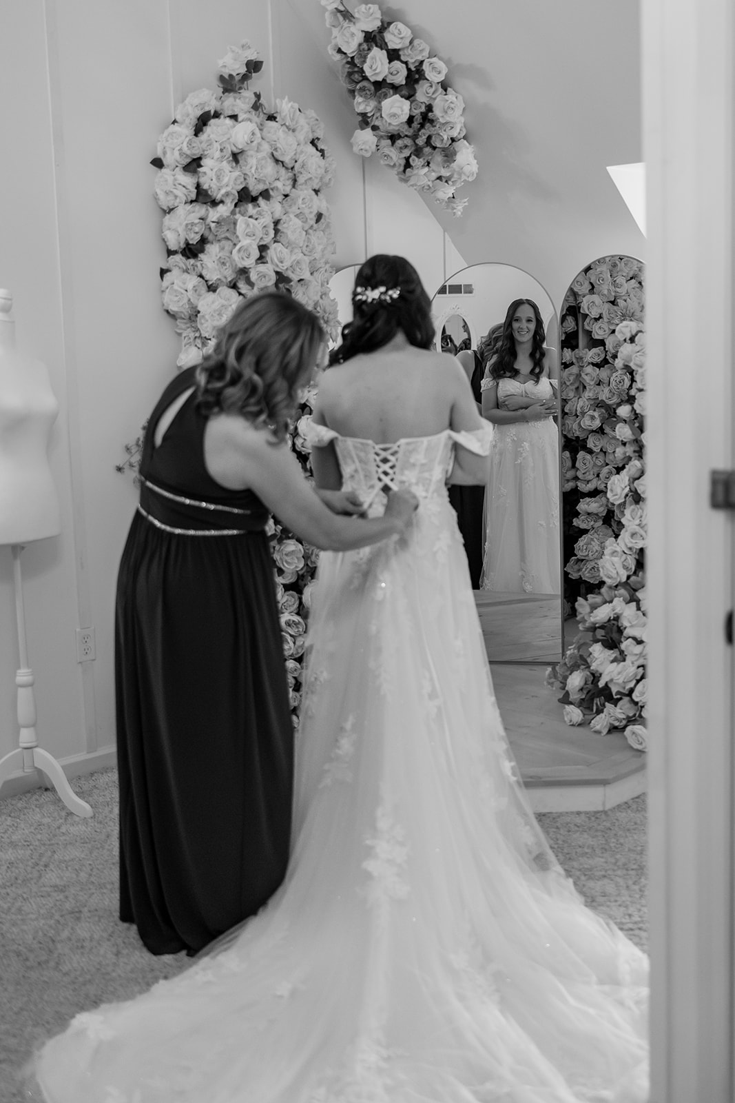 Brides mom helps her put on her wedding dress