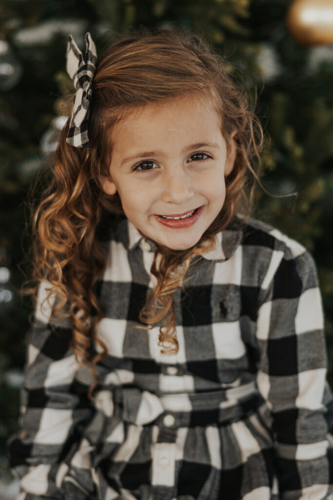 Young girl smiles during her family's studio Christmas photoshoot