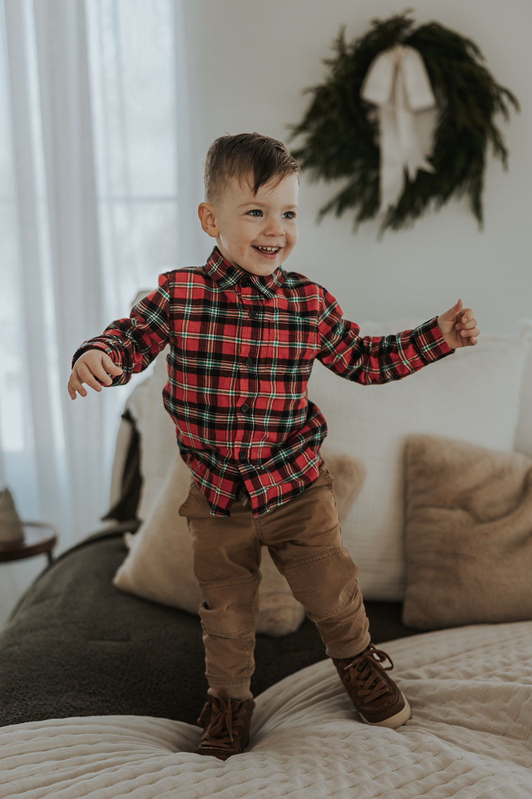 Young boy jumps on the couch during his families Christmas photoshoot