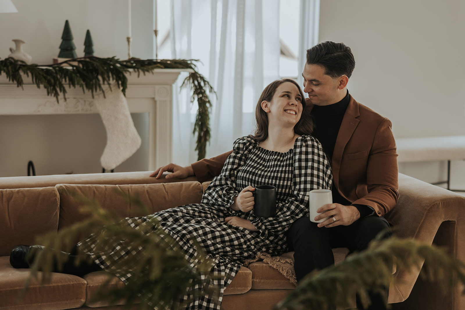 Man and woman pose together on a couch during a Christmas studio photoshoot