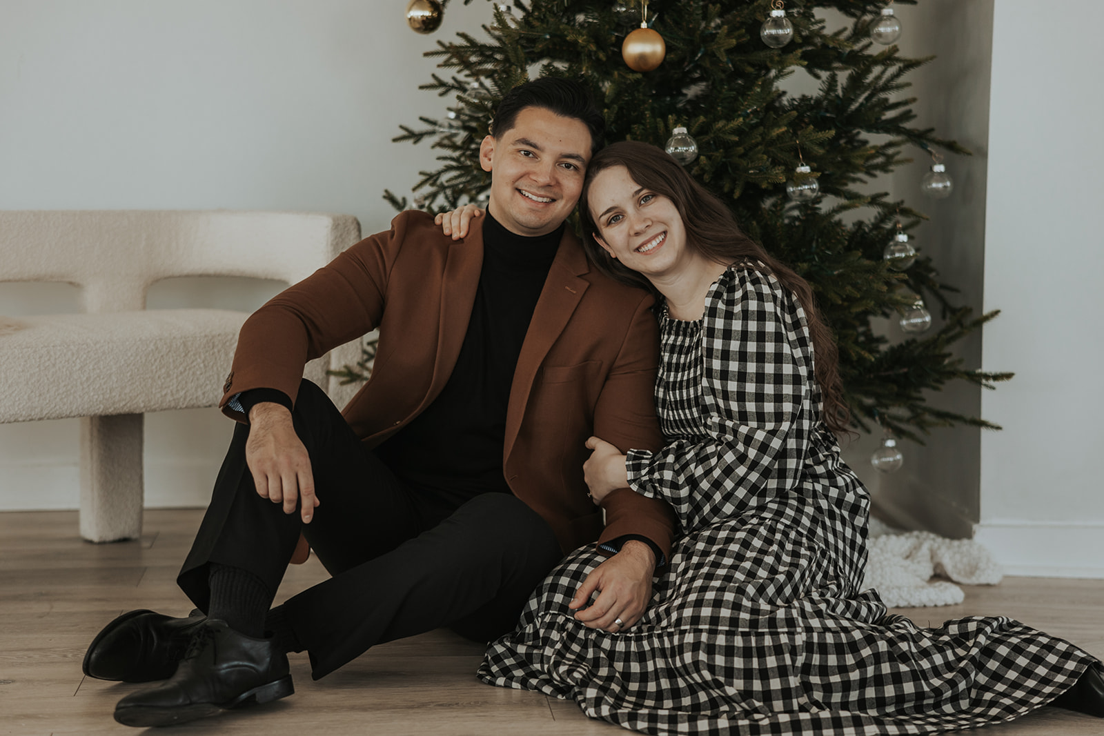 Stunning couple pose in front of a Christmas tree during their Christmas photoshoot