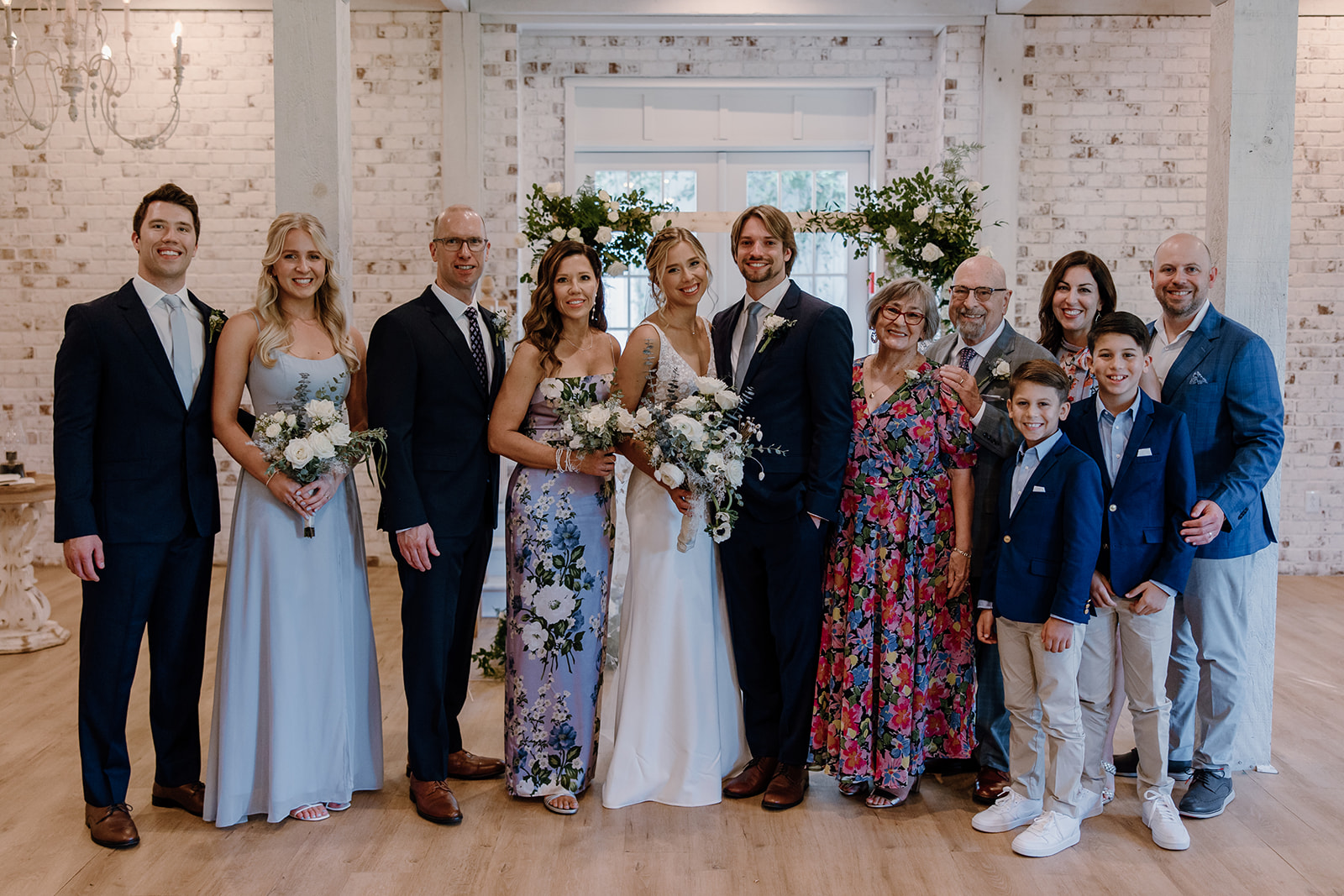 The families pose together on their children's dreamy Georgia wedding day at wildflower barn at little river farms