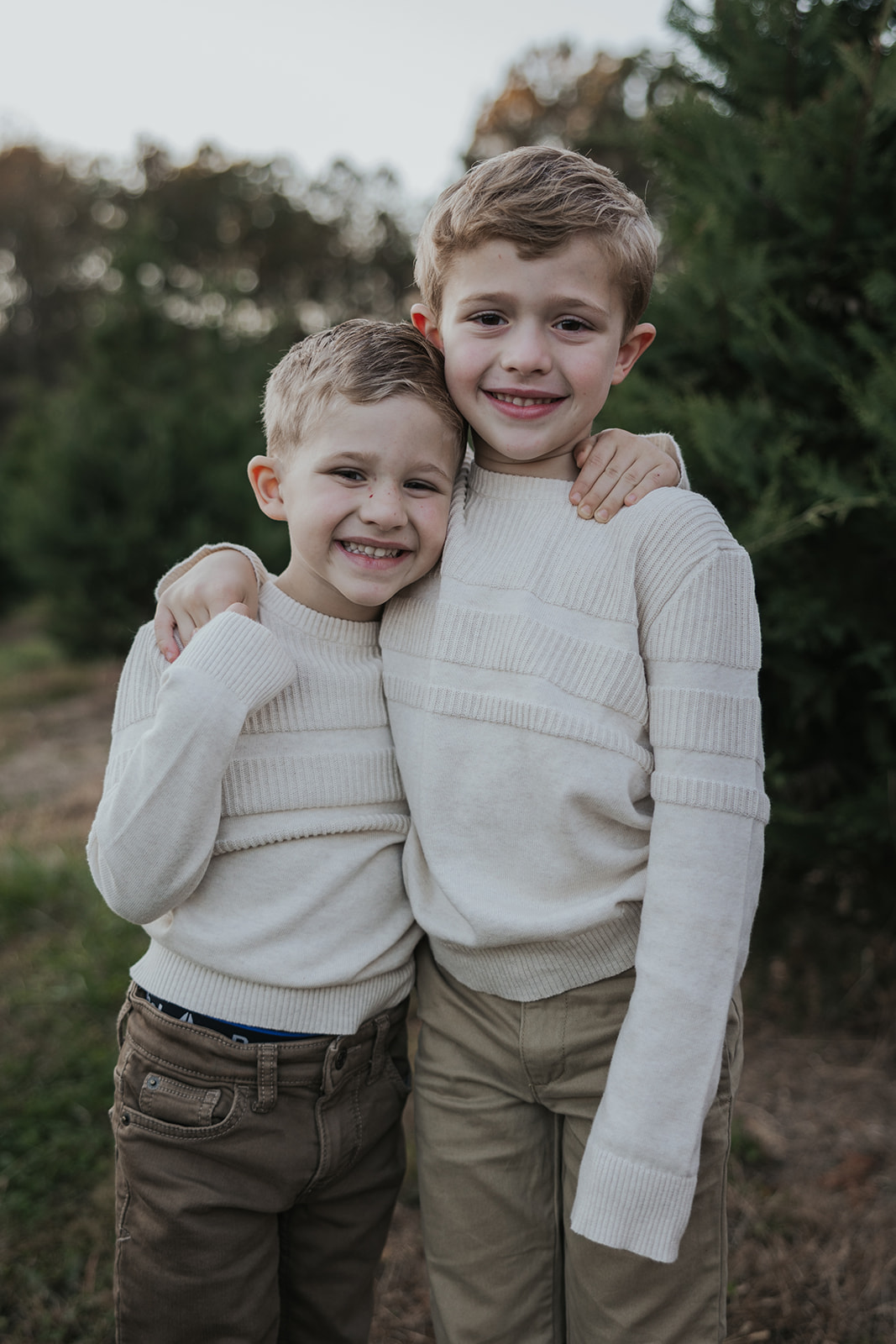 Handsome brother pose together during their families Christmas tree farm family photos