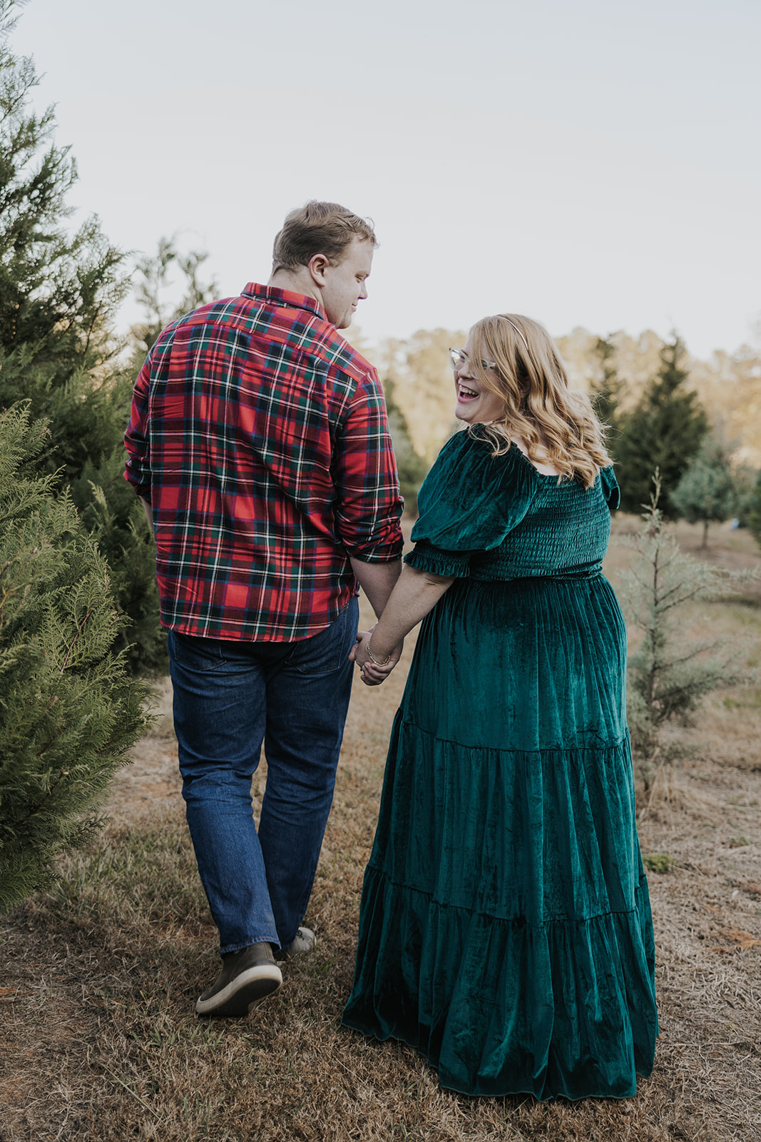 Beautiful walk holding hands sharing a laugh during their Christmas tree farm family photos