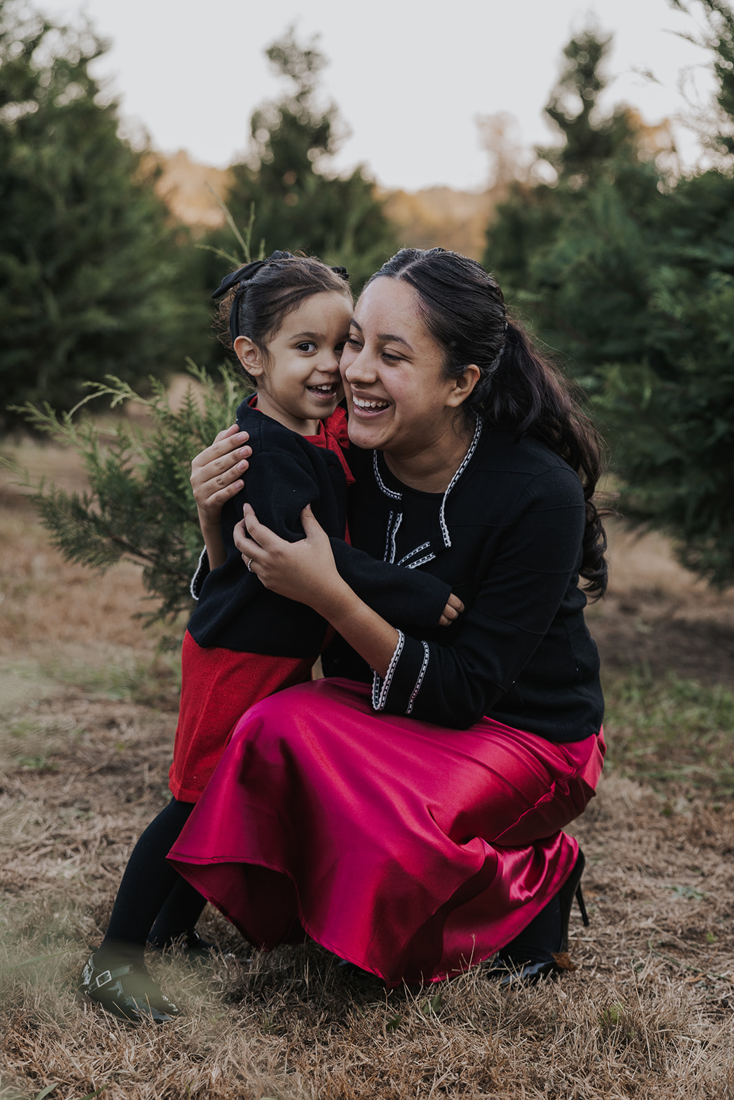 Mom and daughter pose together during their Christmas tree farm family photos