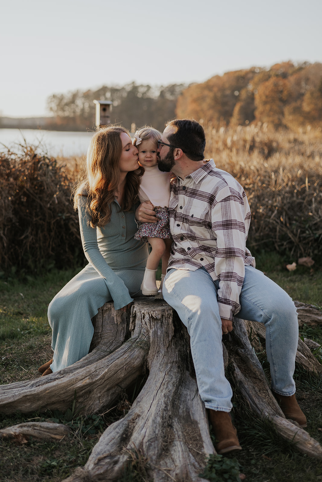 Mom and dad give their young daughter a kiss on the cheek during their Georgia family photoshoot