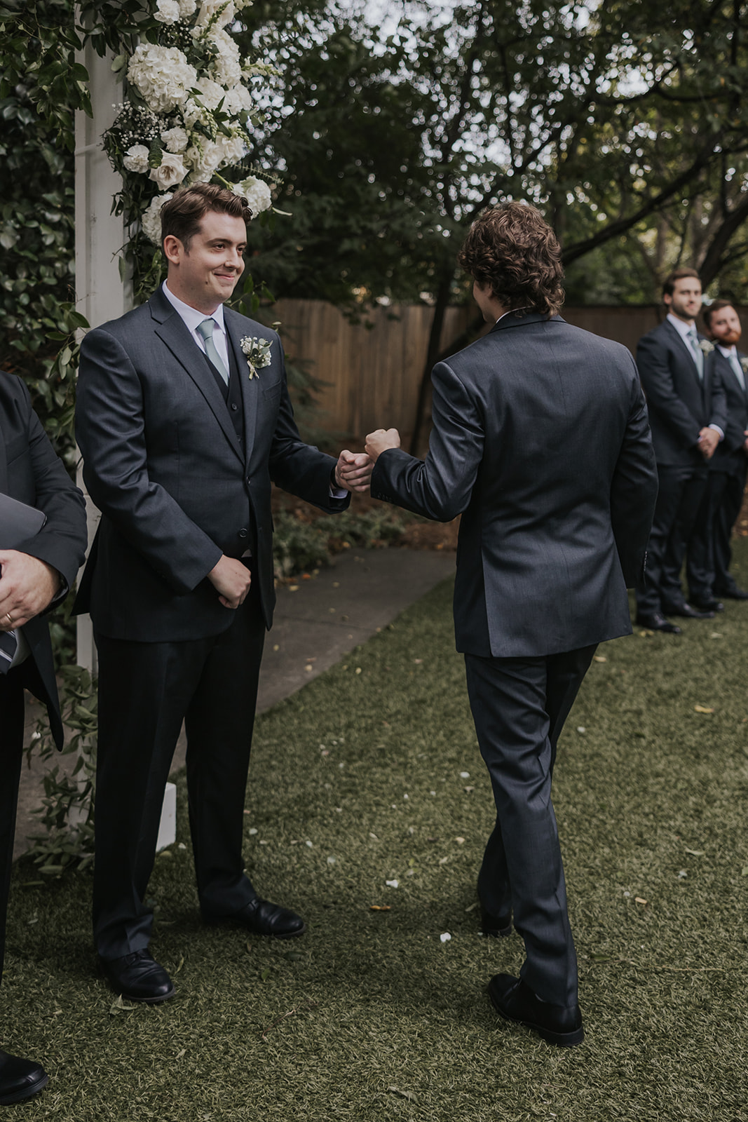 Groom fist bumps a groomsmen as the ceremony is beginning