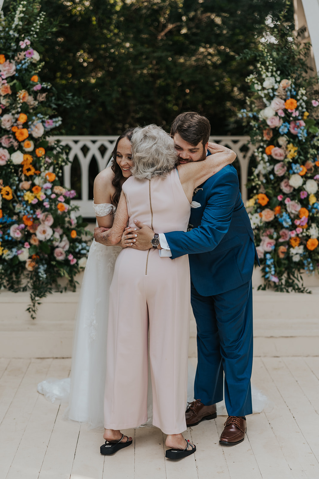 bride and groom share a hug with a grandma