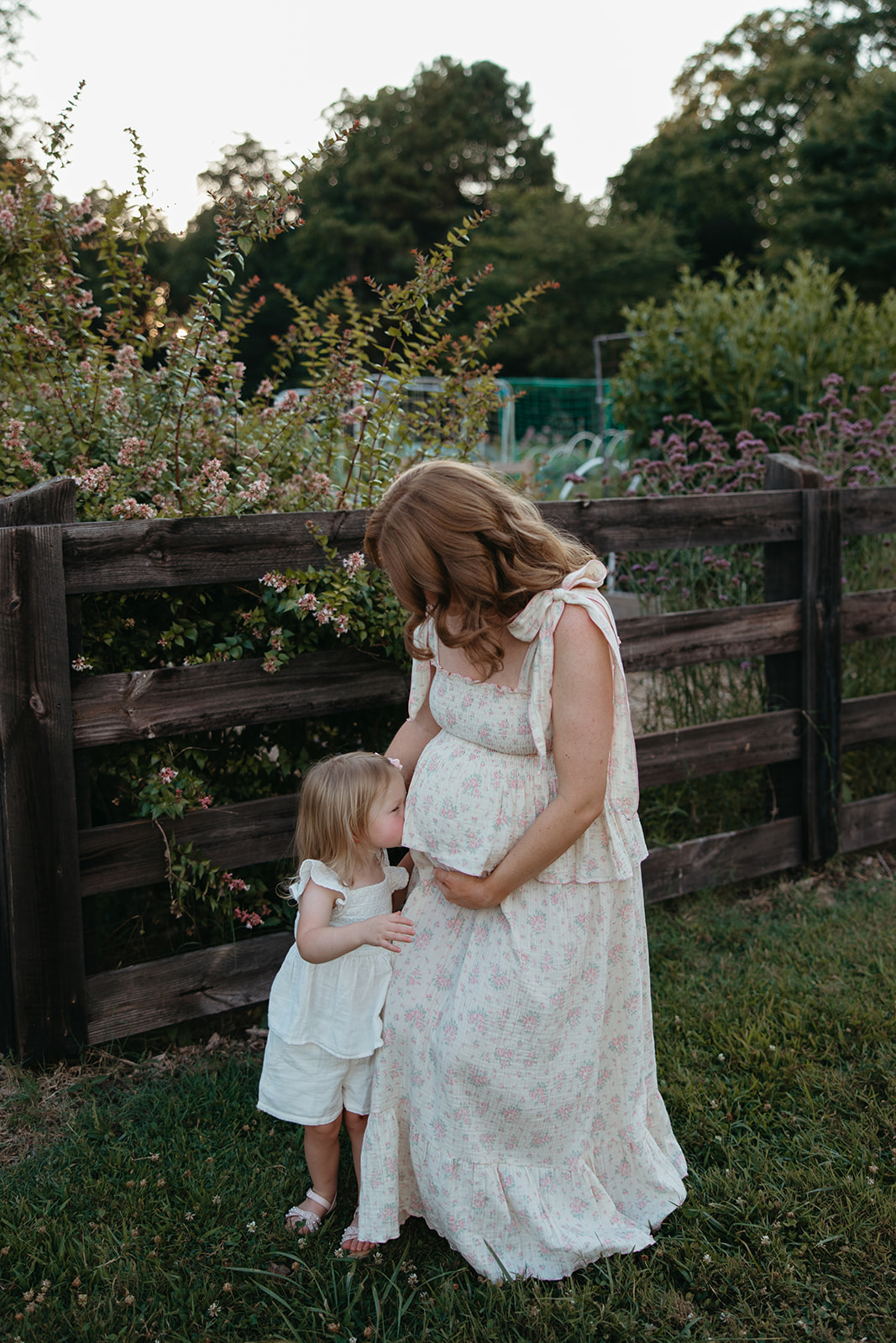 mom and daughter take a photo together during their outdoor maternity photoshoot