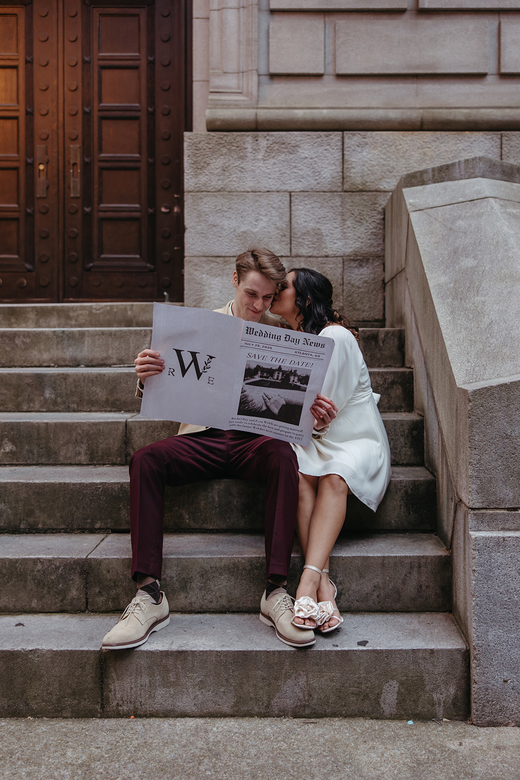 couple sits on the stairs reading a prop newspaper