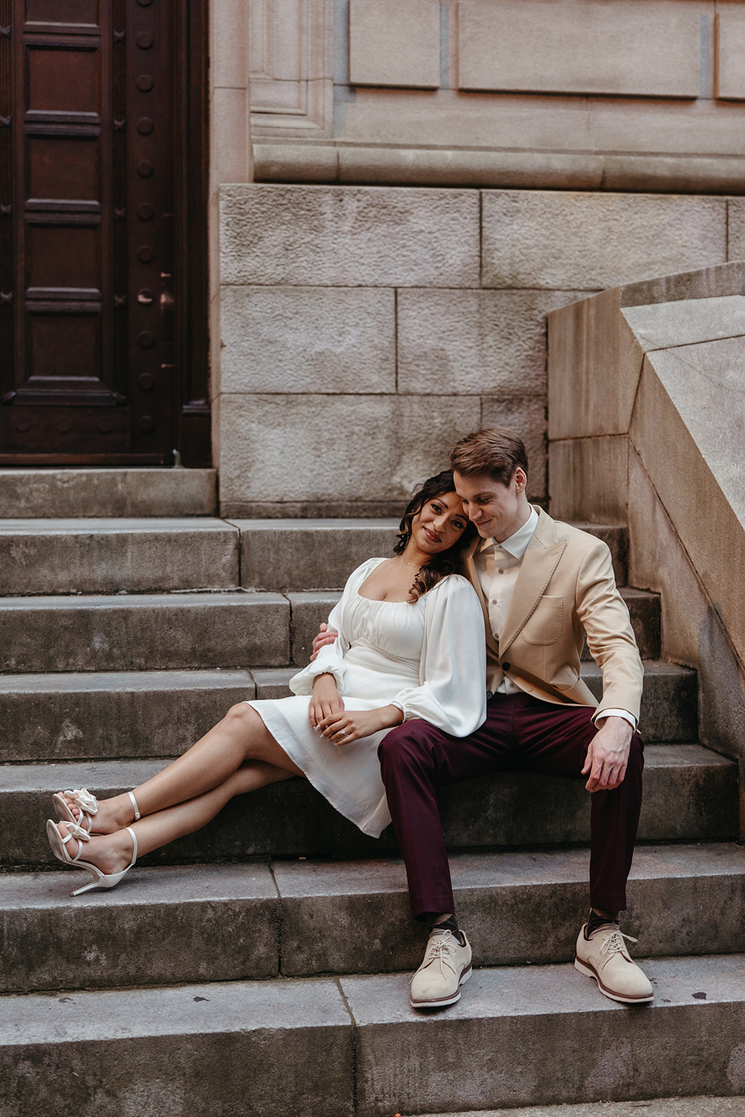 couple sits on the stairs reading a prop newspaper