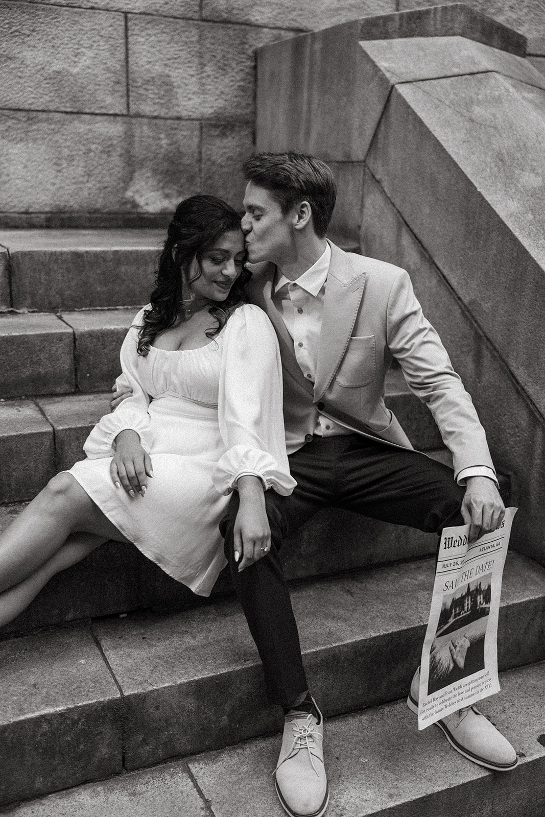 couple sits on the stairs reading a prop newspaper