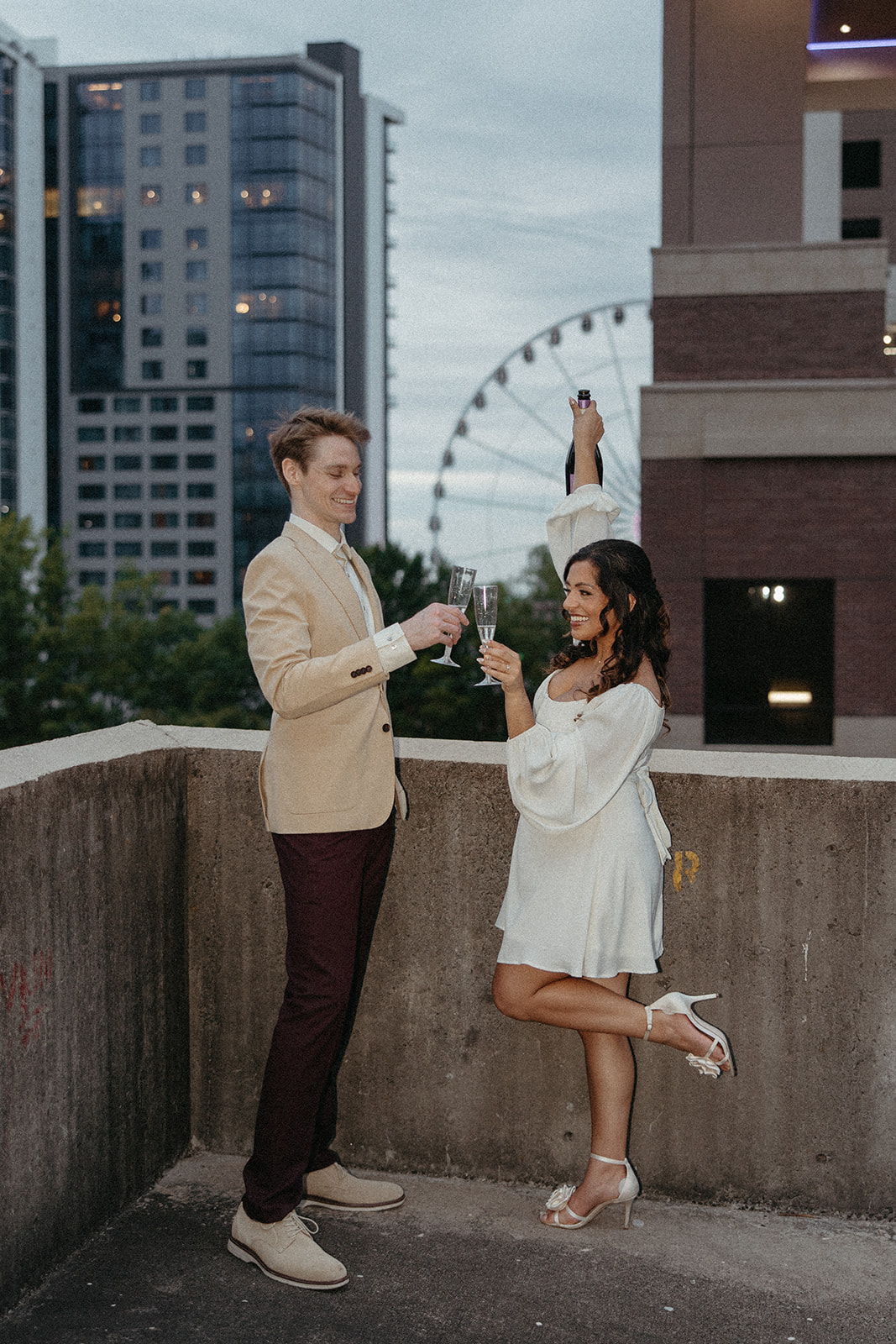 couple pose with glasses of champagne to celebrate their Georgia engagement photos