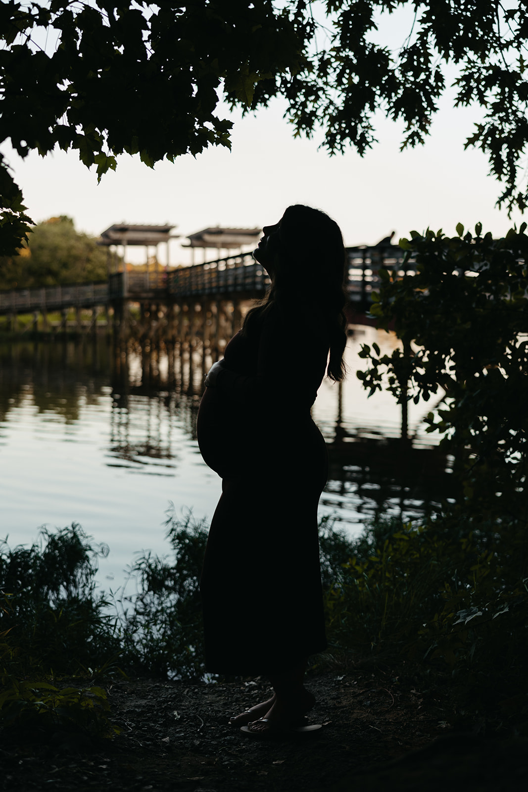 stunning future mom poses for a maternity photo lakeside