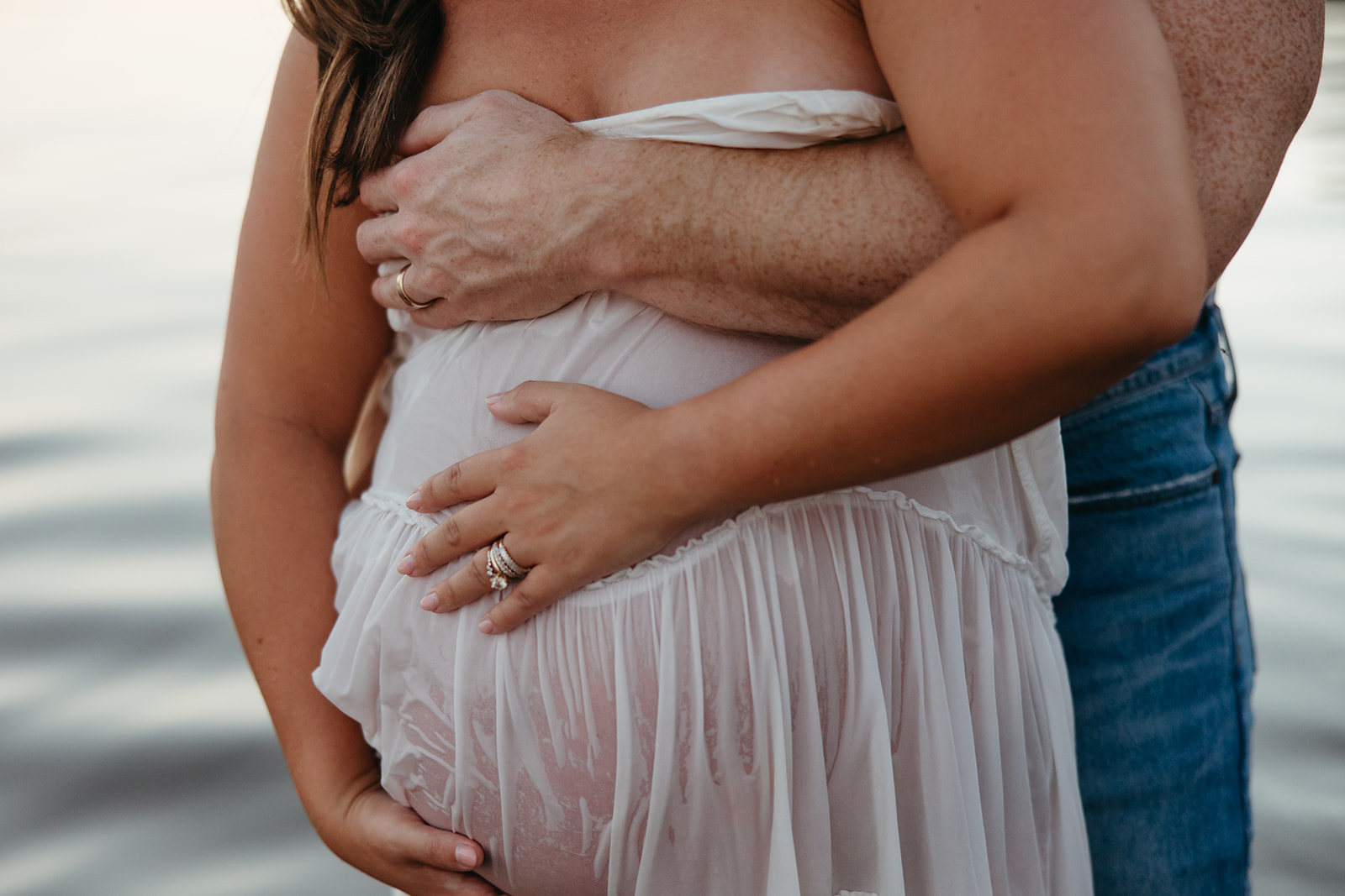 future parents pose together for a photo in the lake