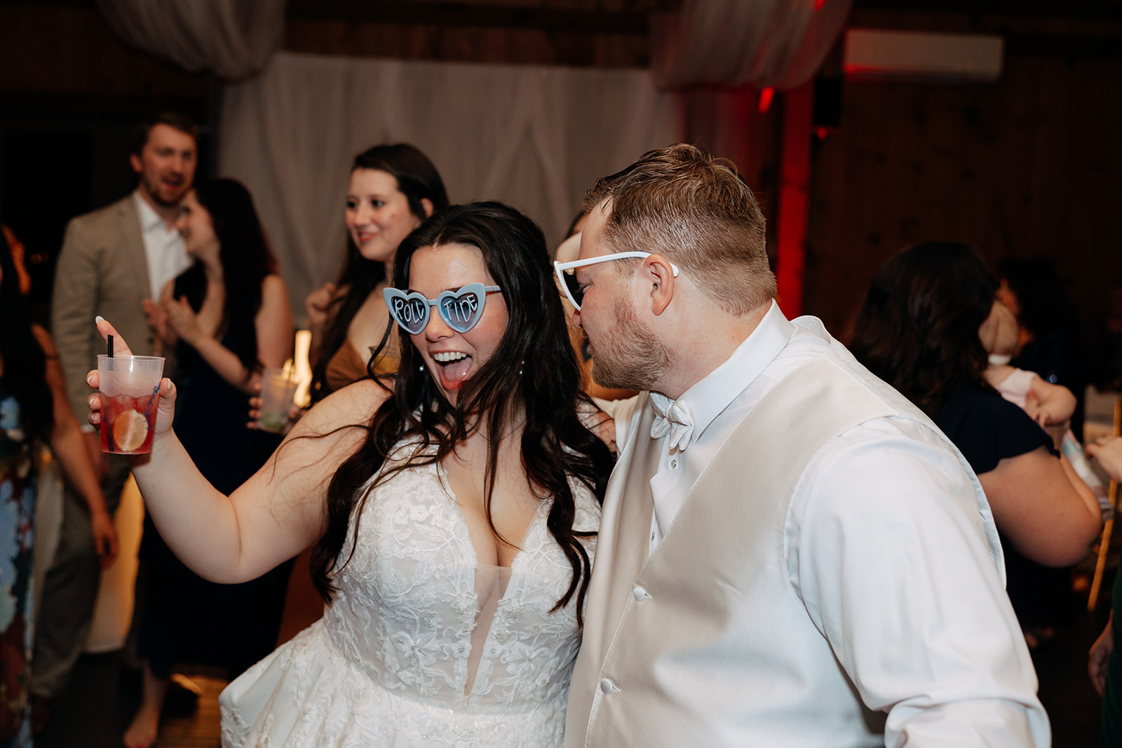 bride and groom share laughs and drinks during their wedding reception