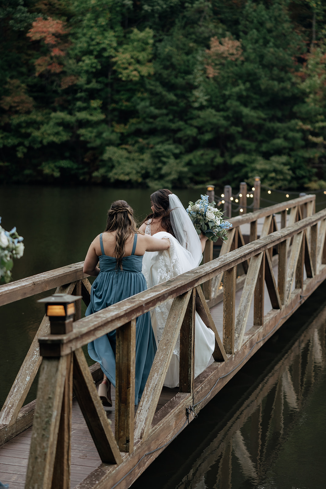 bride gets help walking across dock so her dress doesn't slip off the side