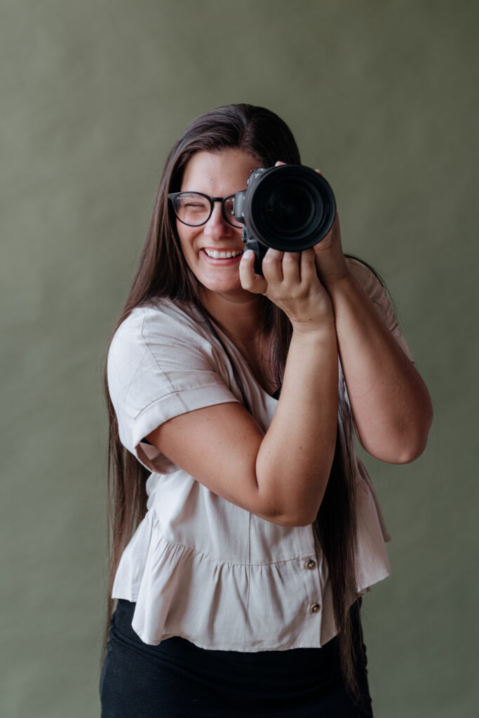 Rachel boyd holds up camera to take a picture in atlanta studio