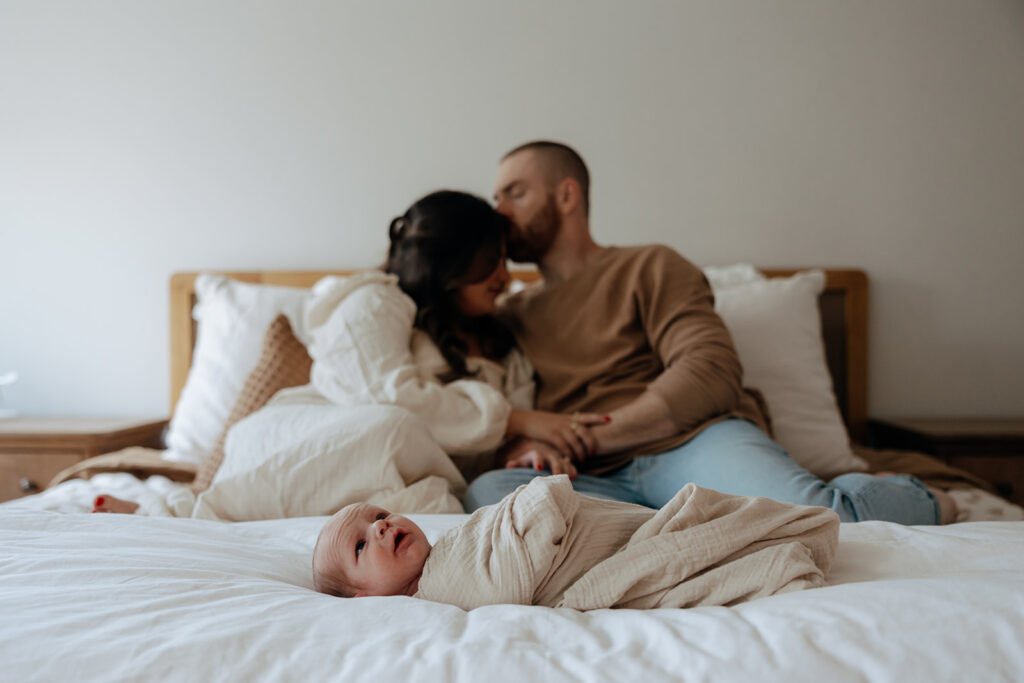 mother and father embrace each there during newborn photoshoot