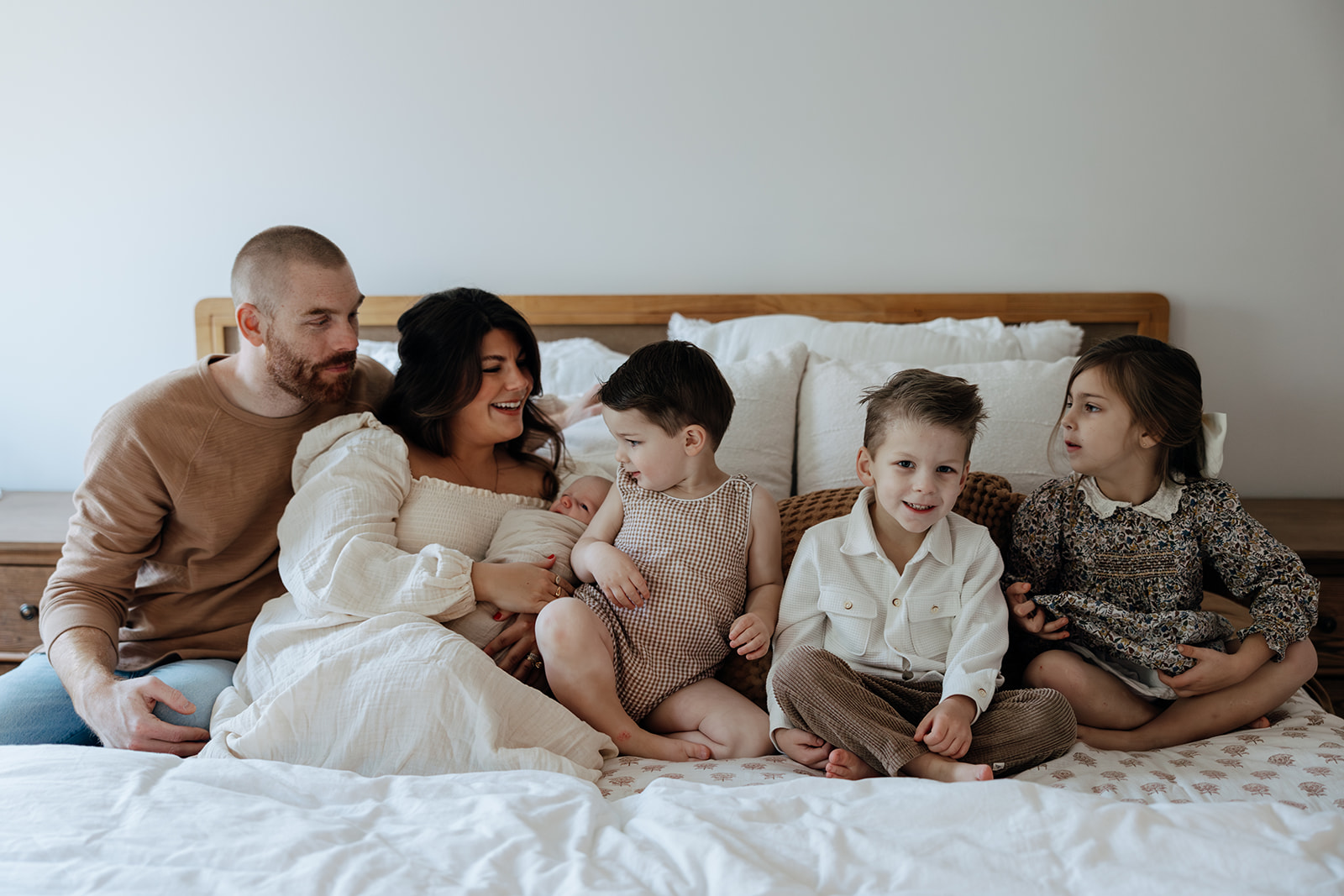 family pose on a bed together with their newborn