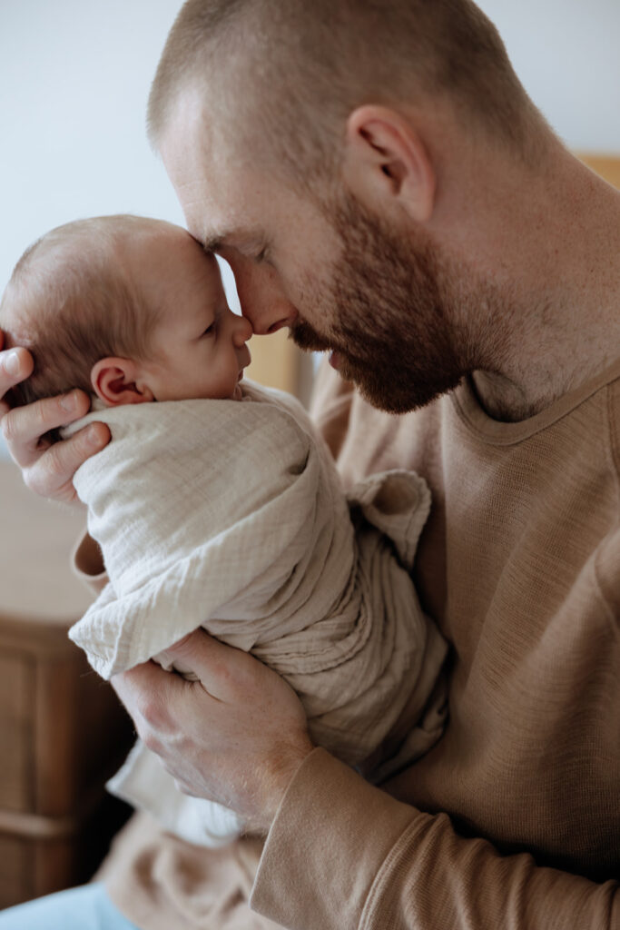 father snuggles new baby 