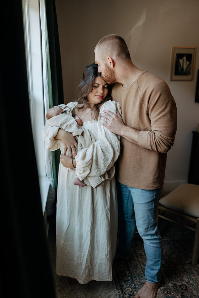 mother and father embrace each other during newborn photoshoot