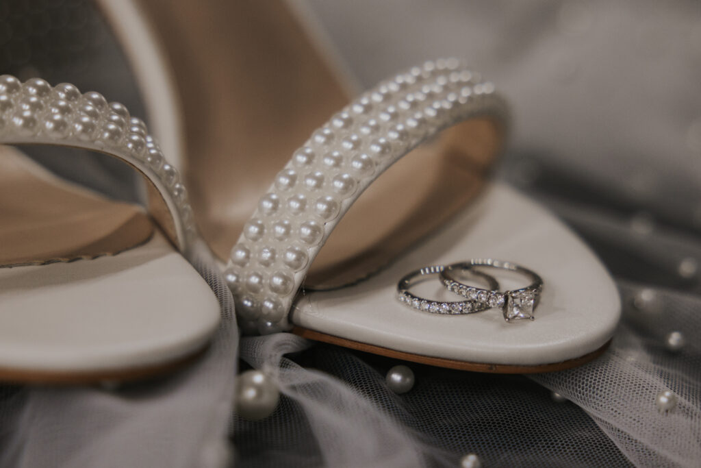 brides wedding rings sitting on wedding shoes and wedding veil