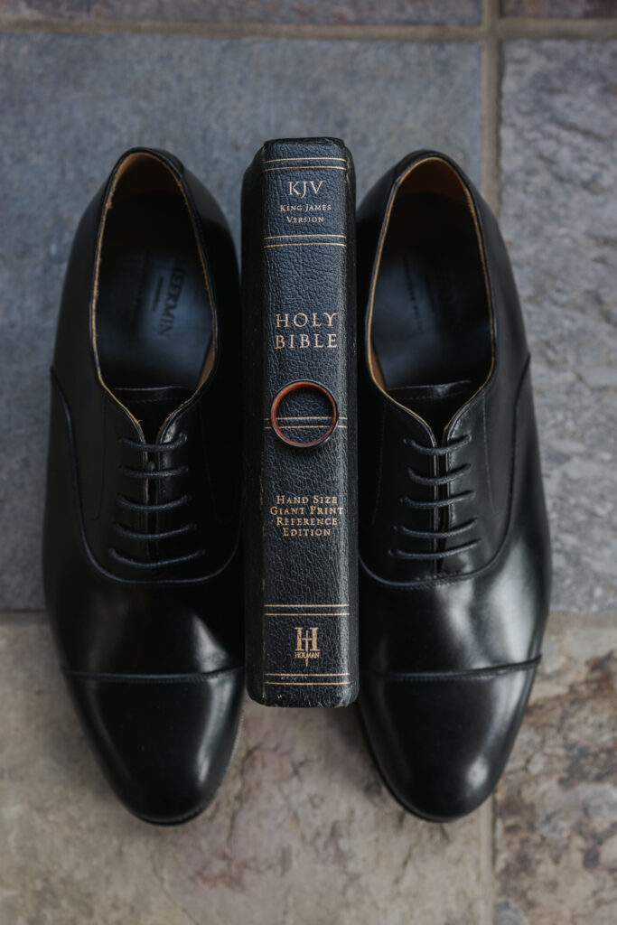 grooms wedding shoes propping up a bible with grooms wedding ring on it