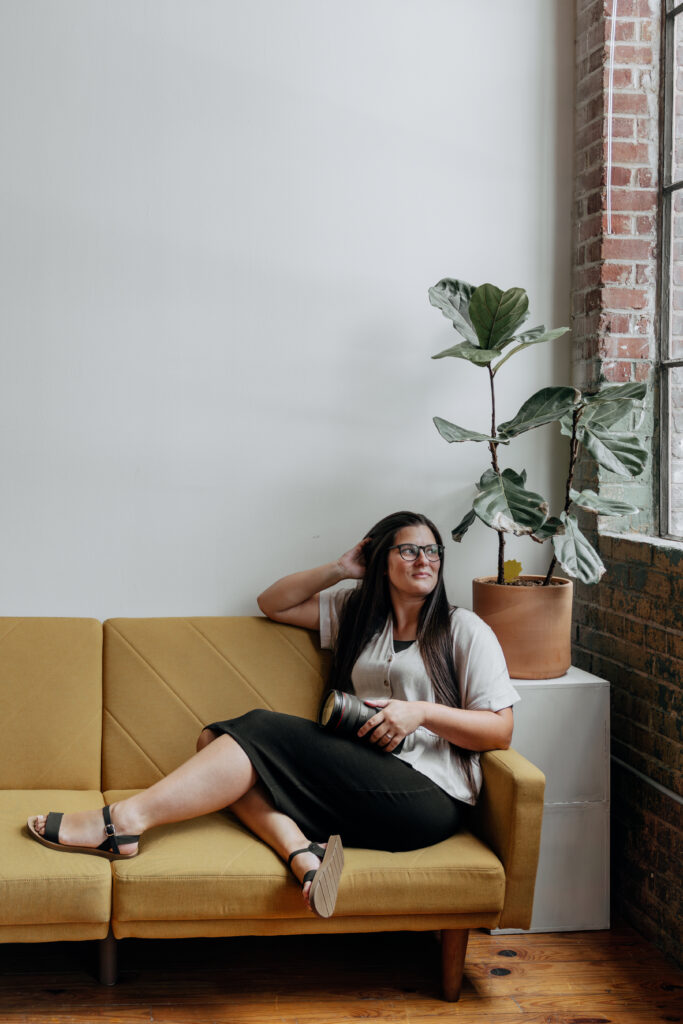 Atlanta wedding photographer posing on a couch with her camera