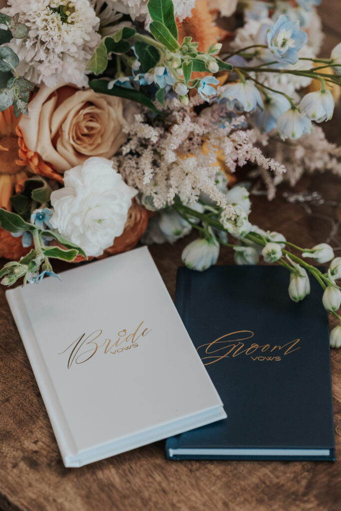 wedding vow books laying on a table with a wedding bouquet