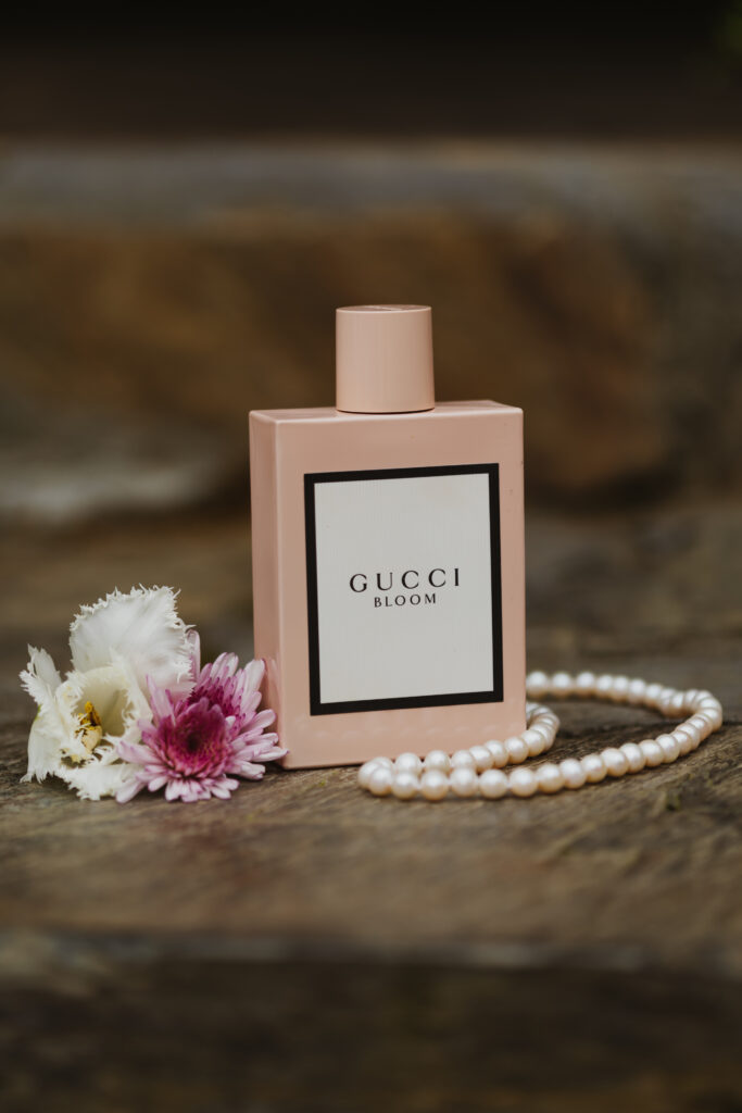 brides perfume bottle next to wedding flowers and brides necklace