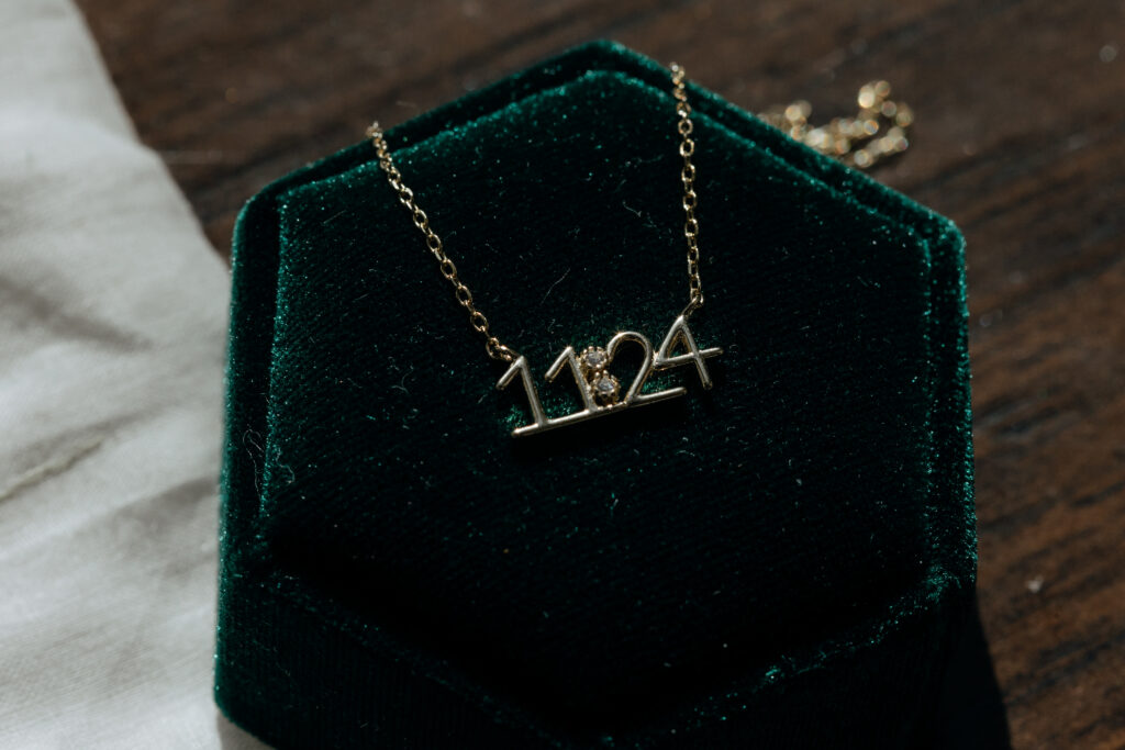 necklace of a brides wedding date laying on a wedding ring box