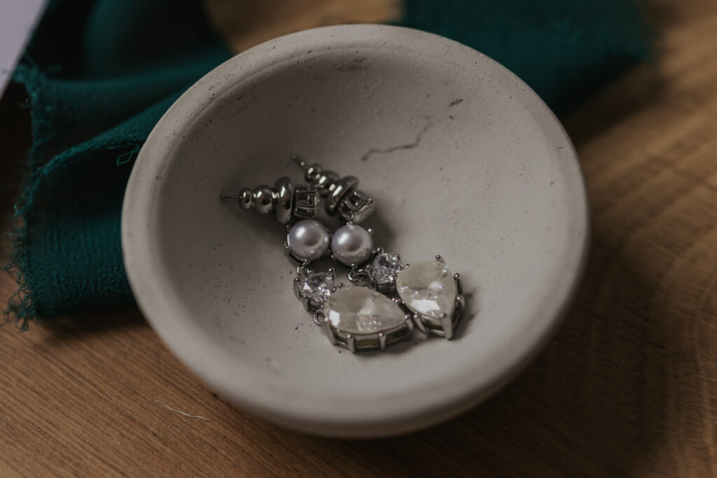 brides wedding earrings laying in a stone bowl