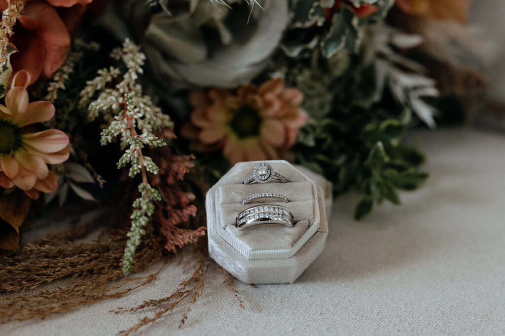 wedding rings in a box next to brides bouquet