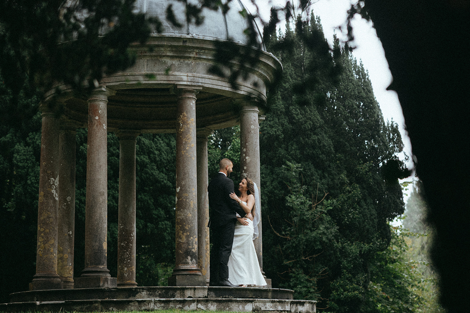 beautiful couple pose for a photo under a gazebo
