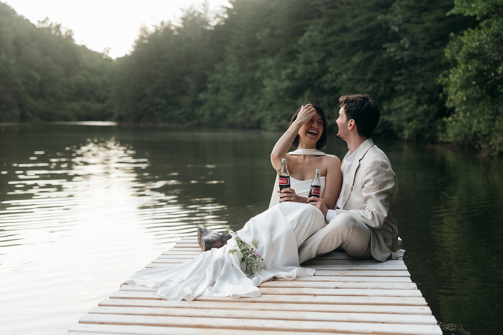 couple share cokes and laughs on the edge of the dock as their Georgia elopement day winds down
